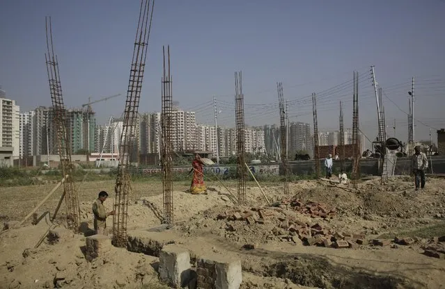 Indian workers work on a building being constructed on an agricultural land on Earth Day in New Delhi, India, Wednesday, April 22, 2015. The world marks Earth Day on April 22 to increase awareness and to promote practices for the sustainability and protection of the Earth's natural environment. (Photo by Altaf Qadri/AP Photo)