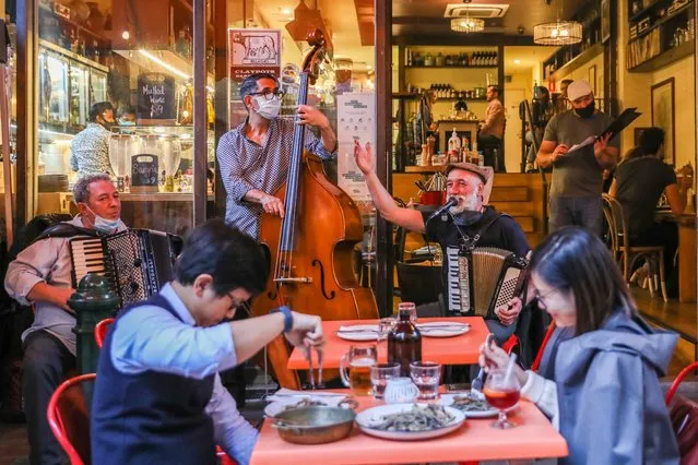 Diners at a restaurant are seen as a band plays at the front of a restaurant on October 22, 2021 in Melbourne, Australia. Lockdown restrictions have lifted in Melbourne after Victoria achieved its target of having 70 per cent of the eligible population fully vaccinated against COVID-19. As of midnight, the curfew for residents in metropolitan Melbourne no longer apply, along with travel limits within the city (although travel to regional Victoria is still not be permitted). The six reasons to leave home no longer apply and home visits with restrictions are allowed. Hospitality can reopen, along with outdoor entertainment and recreation facilities but only to fully vaccinated patrons. Melbourne has endured 263 days in lockdown since March 2020 due to coronavirus outbreaks. (Photo by Asanka Ratnayake/Getty Images)