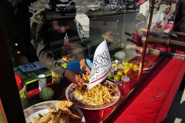 A Taliban flag of the Islamic Emirate of Afghanistan is attached on a food street cart at a market in Kabul, Afghanistan on October 18, 2021. (Photo by Zohra Bensemra/Reuters)