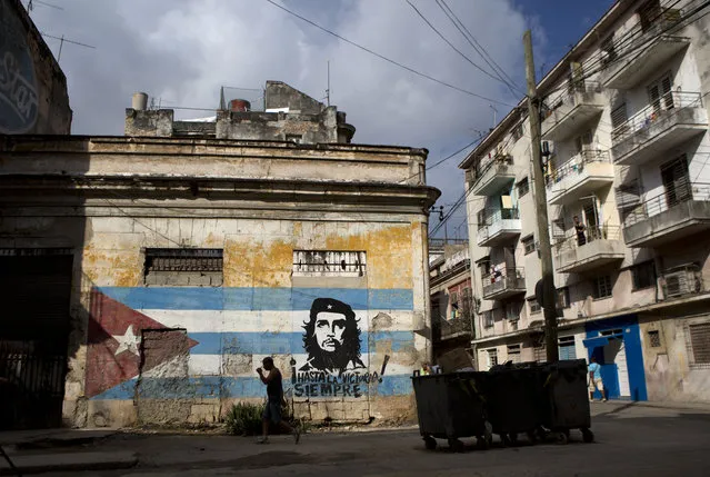 A man walks past a building painted with a Cuban flag and an image of Che Guevara, along with the Spanish slogan “Always toward victory!” in Havana, Cuba, Saturday, March 19, 2016. (Photo by Rebecca Blackwell/AP Photo)