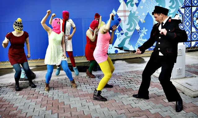 A Cossack militiaman attacks Nadezhda Tolokonnikova as she and fellow members of the punk group p*ssy Riot, including Maria Alekhina, center, in the pink balaclava, stage a protest performance in Sochi, Russia, on Wednesday, February 19, 2014.(Photo by Morry Gash/AP Photo)