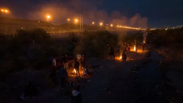 A drone view shows migrants as they encircle fire to keep warm between searching for an entry point into the United States past a razor wire-laden fence from along the bank of the Rio Grande River in El Paso, Texas on March 28, 2024. (Photo by Adrees Latif/Reuters)