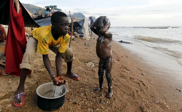 A Burundian refugee washes his kin as they gather on the shores of Lake Tanganyika in Kagunga village in Kigoma region in western Tanzania, to wait for MV Liemba to transport them to Kigoma township, May 17, 2015. (Photo by Thomas Mukoya/Reuters)