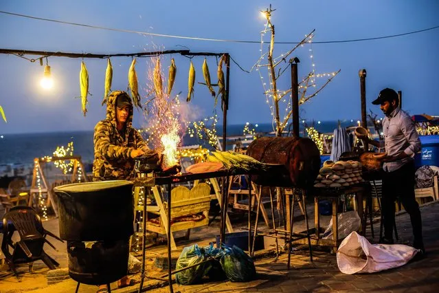 Palestinian street vendors are busy grilling corn and boiling water for coffee at a beach in Gaza City during sunset on November 23, 2021. (Photo by Mahmoud Issa/SOPA Images/Rex Features/Shutterstock)