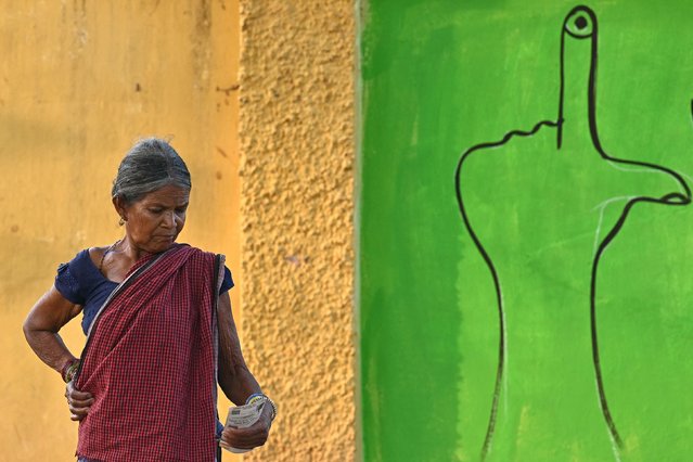 A voter looks on while waiting in front of a voter awareness mural to cast her ballot at a polling station during the first phase of voting of India's general election, in Dugeli village some 33 Km (21 miles) from Dantewada town in Chhattisgarh state on April 19, 2024. As the world's biggest democracy began a six-week election on April 19, thousands of people in villages across Bastar district, one of the last strongholds of the Naxal rebels, cast their ballots. (Photo by Idrees Mohammed/AFP Photo)