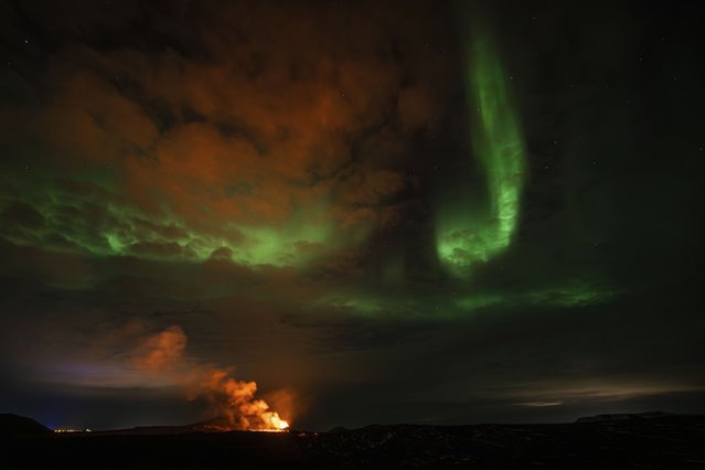 View of the eruption area with the northern lights dancing in the sky near the town of Grindavik, Iceland, Saturday April 6, 2024. The volcano in southwestern Iceland that erupted three times in December, January and February, sending lava towards a nearby community, keeps erupting. (Photo by Marco di Marco/AP Photo)