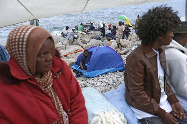 Migrants crowd on the rocky beach at the Franco-Italian border near Menton, southeastern France, Tuesday, June 16, 2015. Some 100 migrants, principally from Eritrea and Sudan, attempted since last Friday, to cross the border from Italy and have been blocked by French and Italian gendarmes. (AP Photo/Lionel Cironneau)