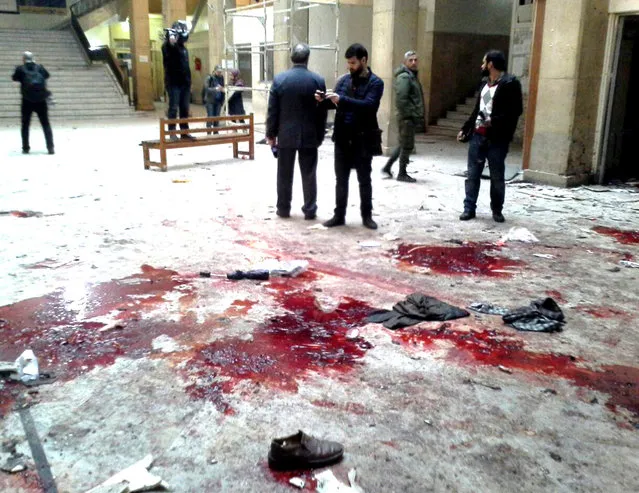 In this photo released by the Syrian official news agency SANA, journalists gather next of blood inside the main judicial building which attacked by a suicide bomber, in Damascus, Syria, Wednesday, March 15, 2017. (Photo by SANA via AP Photo)