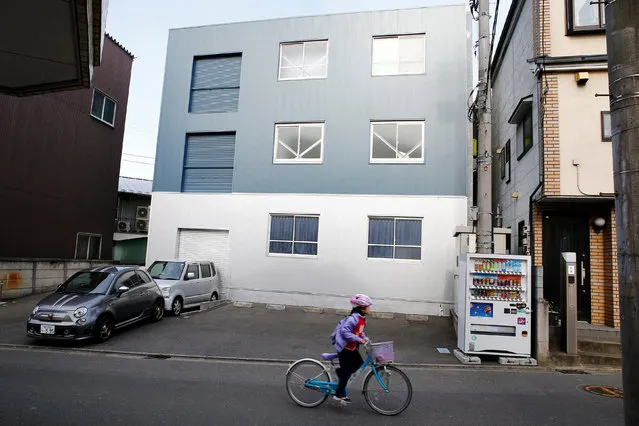 A child cycles past the “Corpse Hotel” in Kawasaki, Japan, April 20, 2016. (Photo by Thomas Peter/Reuters)