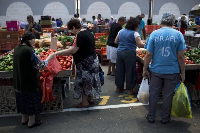 In this Tuesday, June 23, 2015 photo, Israelis buy groceries in an open market in the southern Israeli town of Sderot, next to the Israel-Gaza border. (Photo by Oded Balilty/AP Photo)