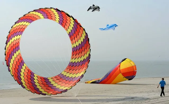 Joerg Beckmann watches his different kites during calm winds from east at the beach of the North Sea island Norderney, Germany, Tuesday, April 22, 2014. (Photo by Ingo Wagner/AP Photo/DPA)