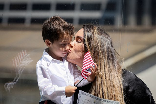 A woman kisses her child following her U.S. Citizenship and Immigration Services (USCIS) naturalization ceremony at the New York Public Library, in New York City on July 2, 2024. (Photo by Brendan McDermid/Reuters)