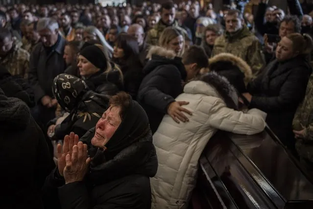 Relatives and friends attend a funeral ceremony for four of the Ukrainian military servicemen, who were killed during an airstrike in a military base in Yarokiv, in a church in Lviv, Ukraine, Tuesday, March 15, 2022. At least 35 people were killed and many wounded in Sunday's Russian missile strike on a military training base near Ukraine's western border with NATO member Poland. (Photo by Bernat Armangue/AP Photo)