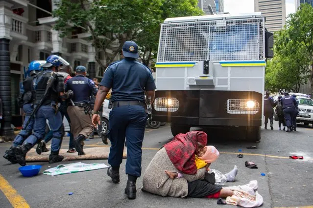 A woman with her baby protest outside the U.N. refugee agency's offices in Cape Town, South Africa Wednesday, October 30, 2019. Police used water cannons while dispersing and arresting scores of foreigners who have camped outside the offices for weeks seeking relocation outside South Africa after a wave of attacks on foreigners in cities earlier this year. (Photo by AP Photo/Stringer)