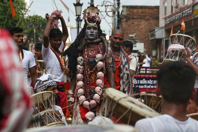 A Hindu devotee is dressed as Lord Shiva and others play drums as they take part in a procession to celebrate a festival dedicated to the Hindu god Lord Shiva, that marks the first Monday of the monsoon (Sawan) month, in Varanasi on July 22, 2024. (Photo by Niharika Kulkarni/AFP Photo)