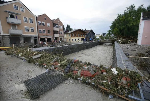 People stand at the bank of river Inn in the flooded Bavarian village of Simbach am Inn east of Munich, Germany, June 1, 2016. (Photo by Michaela Rehle/Reuters)