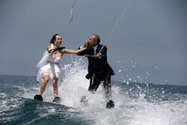 Lebanese groom Tommy kisses the hand of his bride Nadine's while water skiing dressed in their wedding clothes in the waters off the bay of Jounieh, north of Beirut, on May 29, 2017. Tommy and Nadine got married in a civil wedding in Cyprus last week before celebrating in Lebanon. (Photo by Patrick Baz/AFP Photo)
