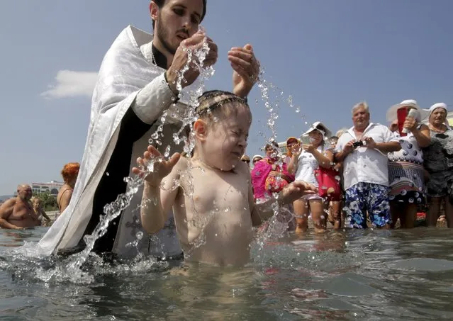 An orthodox priest baptizes a girl in the Black Sea during a ceremony marking the 1,027th anniversary of the Christianisation of Kievan Rus' in Yalta, Crimea, July 28, 2015. Orthodox believers mark on Tuesday the Christianisation of the country, which was known as Kievan Rus' at the time, by its grand prince, Vladimir I (Vladimir the Great), in 988 AD. (Photo by Pavel Rebrov/Reuters)