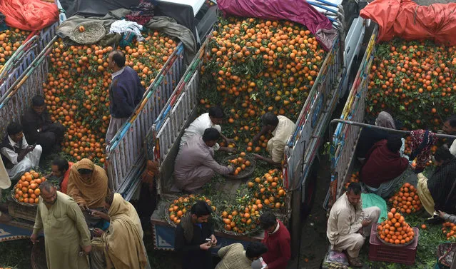 Pakistani traders sell oranges on their trucks at a fruit market in Lahore on December 4, 2016. (Photo by Arif Ali/AFP Photo)