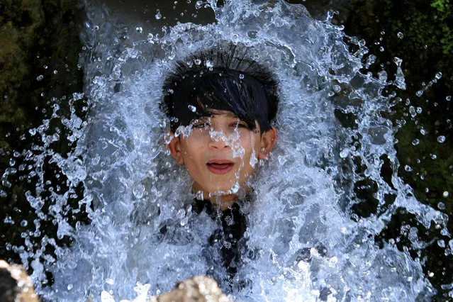 A boy holds his head against a water pipe from a canal flowing under a road bridge on the outskirts of Peshawar, Pakistan June 9, 2017. (Photo by Fayaz Aziz/Reuters)
