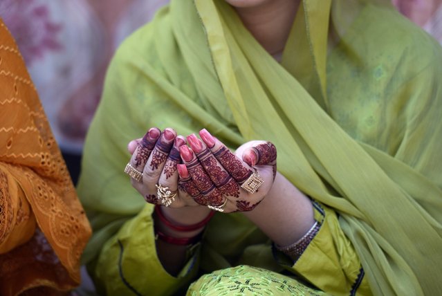 A woman has her hands painted with traditional henna as she attends Eid al-Adha prayers at historical Badshahi mosque in Lahore, Pakistan, Monday, June 17, 2024. Eid al-Adha or Feast of Sacrifice, the most important Islamic holiday, marks the willingness of the Prophet Ibrahim, Abraham to Christians and Jews, to sacrifice his son. During the holiday, which in most places lasts three days, Muslims slaughter goat, sheep or cattle, distribute part of the meat to the poor. (Photo by K.M. Chaudary/AP Photo)