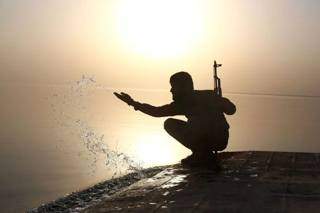 A member of the US-backed Syrian Democratic Forces (SDF), made up of an alliance of Arab and Kurdish fighters, splashes water at the Tabqa dam on April 29, 2017, which has been recently partially recaptured, as part of their battle for the Islamic State's (IS) stronghold in nearby Raqa. The Syrian Democratic Forces now control at least 40 percent of the town of Tabqa, and more than half of its heart, the Old City, the Syrian Observatory for Human Rights monitor said. (Photo by Delil Souleiman/AFP Photo)