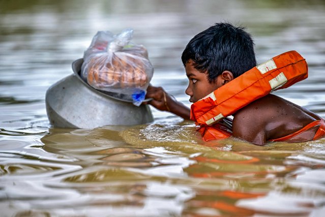 A child wearing a life jacket swims through flood waters after collecting relief materials in Feni, in south-eastern Bangladesh, on August 24, 2024. Nearly 300,000 Bangladeshis were taking refuge in emergency shelters on August 24 from floods that inundated vast areas of the low-lying South Asian country, disaster officials said. The floods were triggered by heavy monsoon rains and have killed at least 42 people in Bangladesh and India since the start of the week, many in landslides. (Photo by Munir Uz Zaman/AFP Photo)