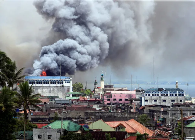 Black smoke comes from a burning building in a commercial area of Osmena street in Marawi city, Philippines June 14, 2017. (Photo by Romeo Ranoco/Reuters)