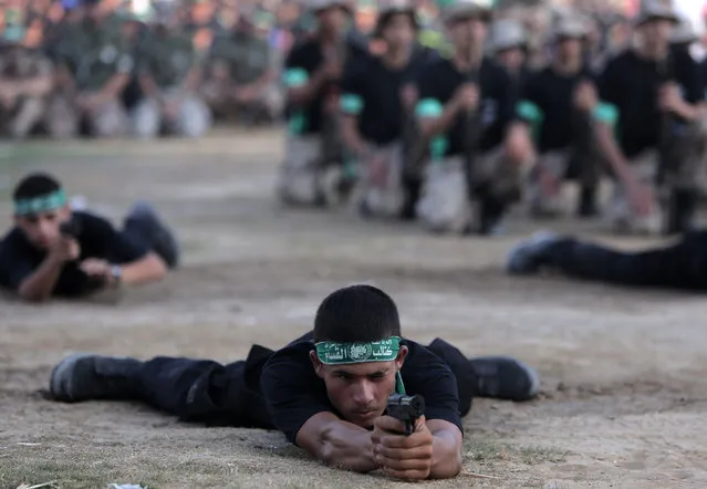 Young Palestinians hold pistols to display their military skills during a graduation ceremony of the Hamas, Liberation Youth, military summer camp, in Gaza City, Wednesday, August 5, 2015. (Photo by Khalil HamraAP Photo)