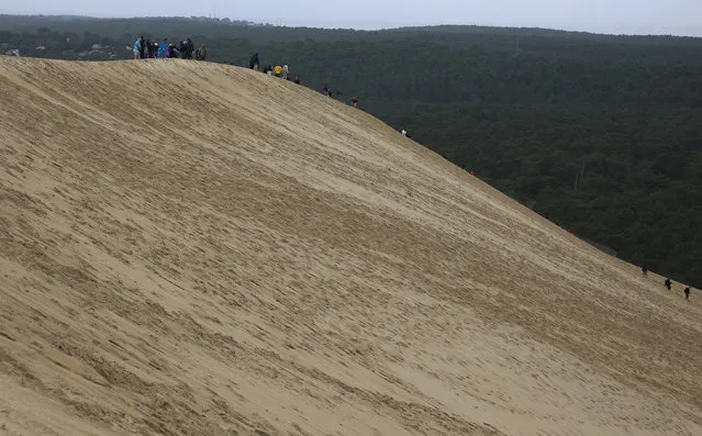 People stand on the top of Dune du Pilat (Dune of Pilat), the tallest sand dune in Europe, in La Teste de Buch, near Bordeaux, France, June 15, 2016. (Photo by Sergio Perez/Reuters)