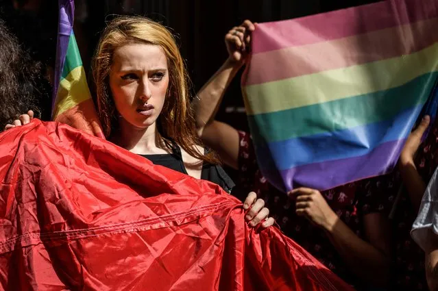 A woman holds rainbow flag as Turkish anti-riot police officers fire rubber bullets to disperse demonstrators gathered for a rally staged by the LGBT community on Istiklal avenue in Istanbul on June 19, 2016. (Photo by Ozan Kose/AFP Photo)