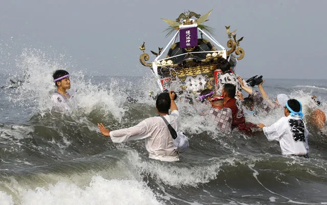 Participants cheer on a portable shrine carried by others as they parade through the sea during a purification rite at the annual Hamaori Festival at Southern beach in Chigasaki, west of Tokyo Monday, July 17, 2017. (Photo by Shizuo Kambayashi/AP Photo)