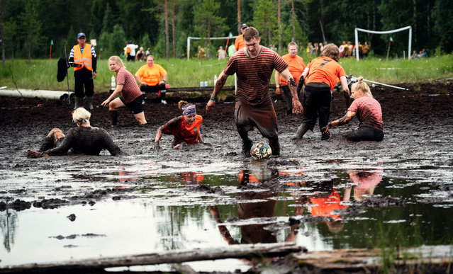 Players vie for the ball during a match of swamp soccer on July 15, 2023 at the Swamp Soccer World Cup in the swamps of Vuorisuo in Hyrynsalmi municipality, Finland. The annual Swamp Soccer World Cup that took place from July 14 to 15, 2023 saw players fight for the ball amidst deep quagmires, with over a hundred teams gathered in the wetlands of central Finland in Hyrynsalmi. While most of the ruleset is consistent with traditional soccer, there are only five players on the field, as well as a goalkeeper, and the playing time consists of two halves of ten minutes each. (Photo by Alessandro Rampazzo/AFP Photo)