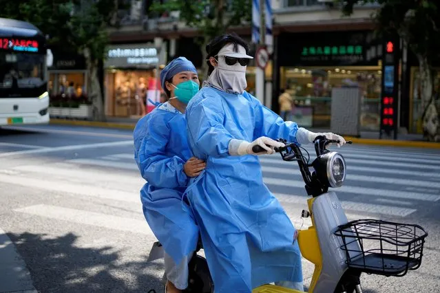 Women in protective suits ride an electric scooter on a street, amid new lockdown measures in parts of the city to curb the coronavirus disease (COVID-19) outbreak in Shanghai, China. on June 15, 2022. (Photo by Aly Song/Reuters)