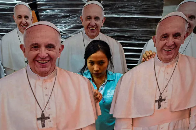 A woman stands amid life- size images of Pope Francis at a printing centre in Cali, Colombia, on August 15, 2017. Pope Francis will make a special four- day visit to Colombia, from September 6 to 11, to add his weight to the process of reconciliation between the government and the FARC. (Photo by Luis Robayo/AFP Photo)