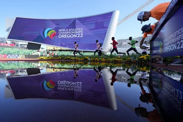 Athletes train while workers put up signage before the World Athletics Championships Thursday, July 14, 2022, in Eugene, Ore. (Photo by Charlie Riedel/AP Photo)