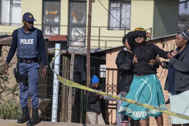 A relative of one of the victims cries as south African Police Service officers refuse to let her cross the police barrier and enter the crime scene in Soweto, South Africa, on July 10, 2022. Fourteen people were killed during a shootout in a bar in Soweto police said on July 10, 2022. Police lieutenant Elias Mawela said that they were called in the early hours in the morning, around 12:30am after the shooting overnight Saturday and Sunday. When police arrived at the scene, 12 people were confirmed dead. 11 others were taken to hospital with wounds but two later died, raising the death toll to 14. (Photo by Ihsaan Haffejee/AFP Photo)