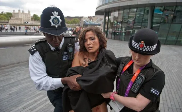 British policemen block a topless activist of Ukraine's prominent feminist rights group FEMEN as she was protesting near the Tower Bridge in Central London on August 2, 2012 on day 6 of the London 2012 Olympic games. FEMEN's activists organised an “islamic maraton” to demonstrate against “islamic regimes” they say being supported by the International Olympic Committee. (Photo by Will Oliver/AP Photo)