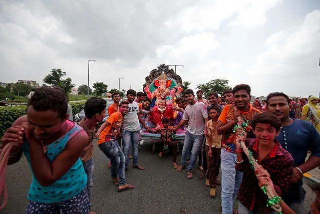 Devotees pull the chariot carrying an idol of the Hindu god Ganesh, the deity of prosperity, for its immersion into the Sabarmati river on the last day of the Ganesh Chaturthi festival, in Ahmedabad, India, September 5, 2017. (Photo by Amit Dave/Reuters)