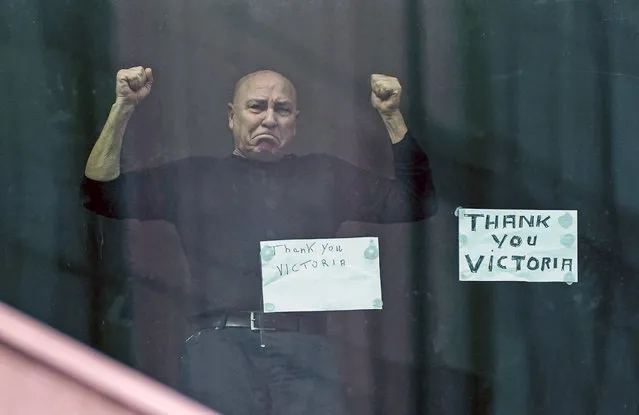 A man gestures from his hotel room as he prepares to leave the Crown Promenade Hotel after spending two weeks in forced quarantine in Melbourne, Australia, 12 April 2020. Health authorities will stagger the release throughout the day of the international arrivals who have completed their mandatory isolation period. A shutdown of non-essential services is in effect Australia wide in a bid to slow the spread of the coronavirus and COVID-19 disease. (Photo by Scott Barbour/EPA/EFE/Rex Features/Shutterstock)