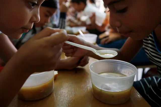 Students enjoy the soup cooked for them during an activity for the end of the school year at the Padre Jose Maria Velaz school in Caracas, Venezuela July 12, 2016. (Photo by Carlos Jasso/Reuters)