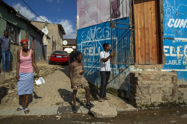Residents watch as South African National Defence Forces, patrol on the street of a densely populated Alexandra township in Johannesburg, South Africa, Thursday, April 16, 2020. South African President Cyril Ramaphosa extended the lockdown by an extra two weeks in a continuing effort to contain the spread of COVID-19 coronavirus. (Photo by Themba Hadebe/AP Photo)