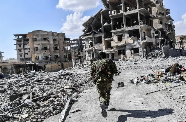 A member of the Syrian Democratic Forces (SDF) runs to take cover from sniper shots near the central hospital of Raqa on October 1, 2017. Syrian fighters backed by US special forces are battling to clear the last remaining Islamic State group jihadists holed up in their crumbling stronghold of Raqa. (Photo by Bulent Kilic/AFP Photo)