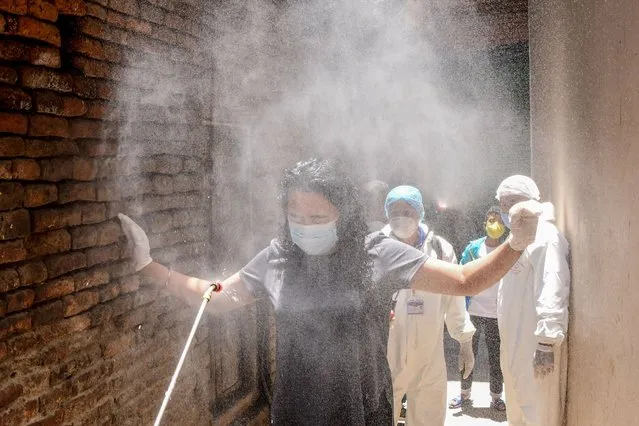 Health workers wearing protective gear spray disinfectant on a local woman (C) in an alley during a government-imposed nationwide lockdown as a preventive measure against the COVID-19 coronavirus, in Kathmandu on May 3, 2020. (Photo by Prakash Mathema/AFP Photo)