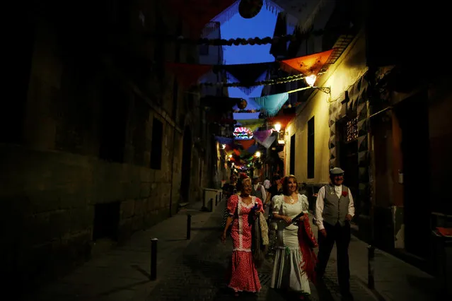 People dressed in traditional attire walk on a decorated street during celebrations to honour San Cayetano (Saint Cajetan) in Madrid, Spain, August 4, 2016. (Photo by Susana Vera/Reuters)