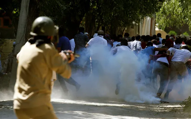Protesters run away as a policeman fires tear gas towards them during a protest against the recent killings in Kashmir, on the outskirts of Srinagar, August 5, 2016. (Photo by Danish Ismail/Reuters)