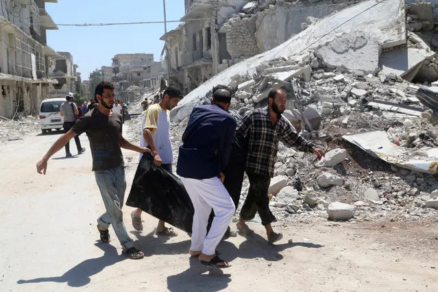 Men carry a dead body near a damaged building after an airstrike on the rebel held Al-Hilwaniyeh neighbourhood in Aleppo, Syria July 14, 2016. (Photo by Abdalrhman Ismail/Reuters)