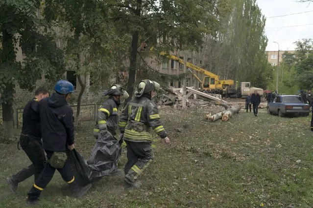 Ukrainian rescue workers carry a bag containing a body of a woman after a Russian attack that heavily damaged a school in Mykolaivka, Ukraine, Wednesday, September 28, 2022. (Photo by Leo Correa/AP Photo)