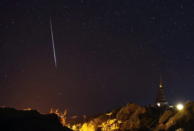A long exposure photo shows a Geminid meteor shower streaking across the night sky next to a pagoda over Doi Inthanon mountain in Chiang Mai province, northern Thailand, early 15 December 2015. Geminids meteor shower can be visible annually in December. It is a phenomenon caused by the object 3200 Phaethon, which its meteors radiate from a radiant of the sky in the constellation of Gemini. (Photo by Rungroj Yongrit/EPA)