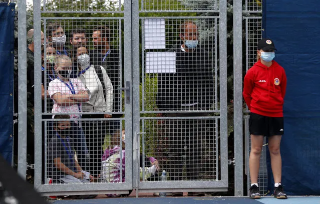 People wearing face masks while standing behind a fence watch the Czech Tennis President's Cup charity tournament final match between Petra Kvitova and Karolina Muchova in Prague, Czech Republic, Thursday, May 28, 2020. The sporting event can take place as the Czech government is taking further steps to ease its restrictive measures adopted to contain the coronavirus pandemic. (Photo by Petr David Josek/AP Photo)